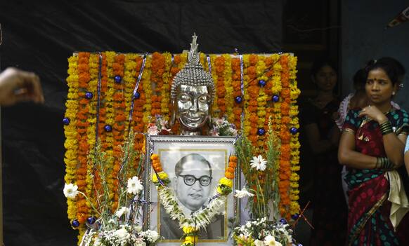 Woman stands near a photo of Bhim Rao Ambedkar displayed beneath a Buddha idol during a procession to mark Ambedkar`s birth anniversary in Mumbai.