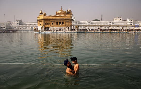 A Sikh man holds a child as they take a holy dip in the sacred pond at the Golden Temple, Sikhs holiest shrine, during Baisakhi festival in Amritsar.