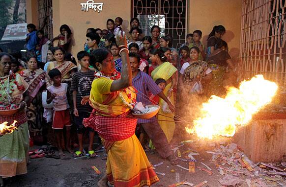Indians watch a Hindu devotee throw fire towards the gate of a Shiva temple during a ritual of Shiva Gajan Hindu festival in Kolkata.