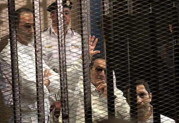 Former Egyptian President Hosni Mubarak, second right, waves at his supporters, who with his sons Alaa, right, and Gamal. left attend a hearing in their retrial on appeal in Cairo, Egypt.