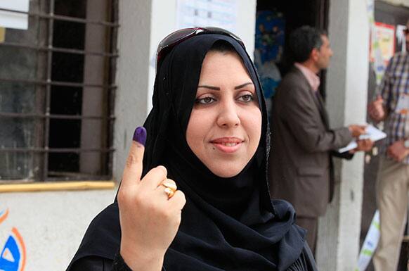 A policewoman displays her ink stained finger, that marks those who have voted, at a polling center during early voting for security forces in the country`s provincial elections in Baghdad, Iraq.
