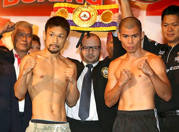 Indonesian WBA featherweight champion Chris John, right, and his opponent Satoshi Hosono of Japan pose for photographers during their official weigh-in in Jakarta.