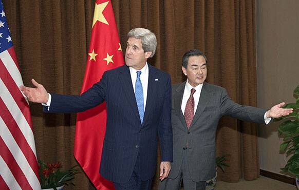 US Secretary of State John Kerry, left, and Chinese Foreign Minister Wang Yi gesture prior to their meeting at the Chinese Foreign Ministry in Beijing.