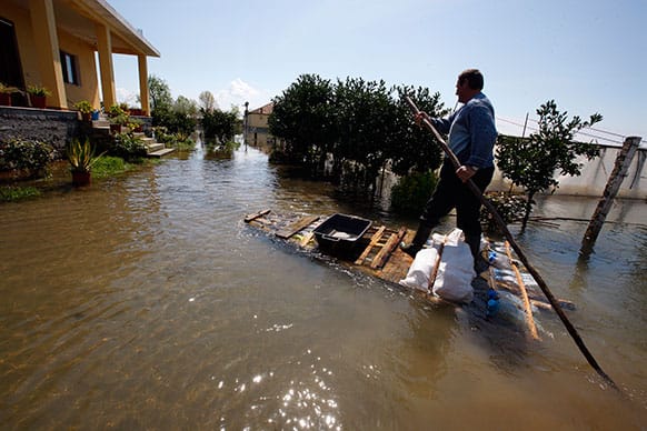 Hil Gjocaj uses a hand-made raft to drive through his yard to his house following a month-long flooding in the village of Obot, near the city of Shkoder, 120 kilometers (75 miles) northwest of capital Tirana.