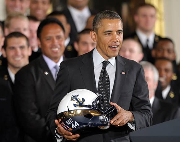 President Barack Obama holds a Navy football team helmet in the East Room of the White House in Washington, after presenting the Commander-in-Chief Trophy to the United States Naval Academy football team.