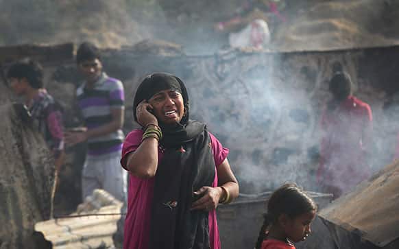 A woman cries while she talks on her mobile phone informing relatives about a fire in which her whole house was burnt in New Delhi.