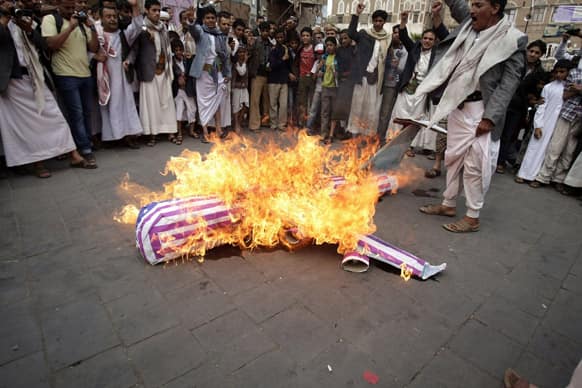 Members of the Yemeni al-Houthi Shiite rebel group burn an effigy of a US aircraft during a demonstration to protest against the US and Saudi interference in Yemen, after Friday prayer in Sanaa, Yemen.