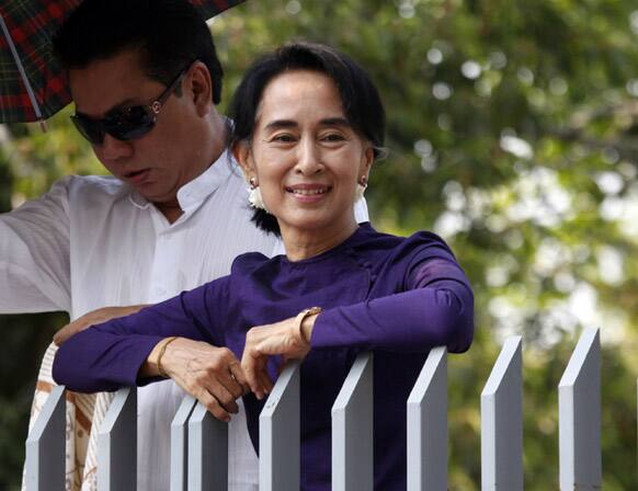 Myanmar opposition leader Aung San Suu Kyi smiles as she watches a performance of an artist troupe from the Free Funeral Service Society at the gate of her residence in Yangon.