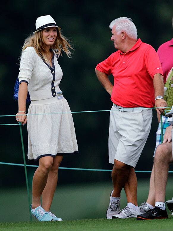 Tennis player Caroline Wozniacki walks with Rory McIlroy`s father Gerry, right, during the first round of the Masters golf tournament.