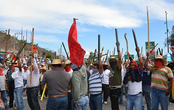 Teachers chant slogans holding up metal pipes and wooden sticks while blocking a major highway in Chilpancingo, Mexico.