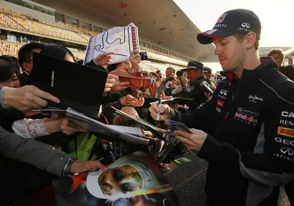 Red Bull driver Sebastian Vettel of Germany signs autographs for fans ahead of the Chinese Formula One Grand Prix in Shanghai.