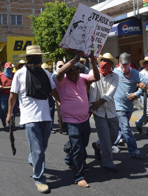 Protesting teachers escort an undercover state policeman, holding up a sign that reads in Spanish