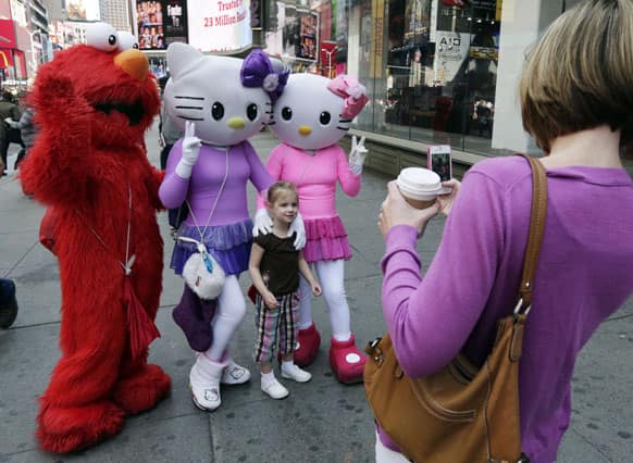 Elmo and two Hello Kitty characters pose for photos with a little girl in New York`s Times Square.