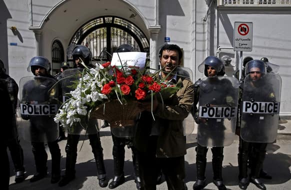 An Iranian student holds bouquet of flowers with a verse from the Holy Quran in Arabic that reads,