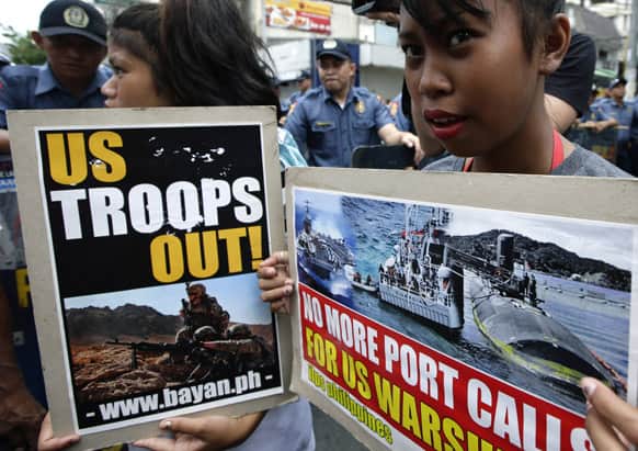 Protesters display placards in front of riot police as the latter prevent them from marching closer to the U.S. Embassy in Manila, Philippines, for a rally against alleged