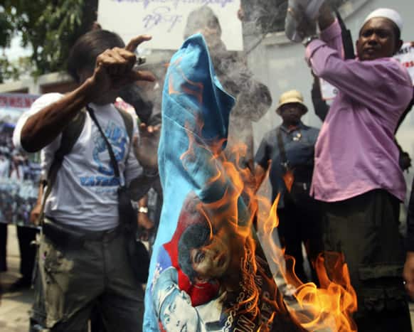 Myanmar Rohingya Muslims burn a T-shirt with an image of Myanmar opposition leader Aung San Suu Kyi, during a protest in front of Myanmar Embassy in Bangkok, Thailand.