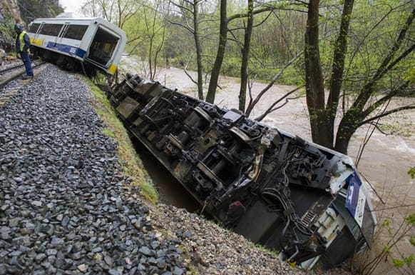Railway workers are seen next to a derailed train carriage near Golbardo, Spain. Spanish authorities say a rockfall derailed the train, injuring 11 passengers after the first carriage partially plunged into a river just west of the northern city of Santander.