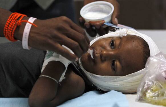 A man feeds ice-cream to a child injured in a building collapse at a hospital on the outskirts of Mumbai.