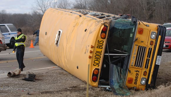 Officials investigate a fatal crash involving two vehicles and a school bus at Route 173 and N. Kilbourne Road near Wadsworth, Ill. One person died and dozens of elementary school children were taken to hospitals.
