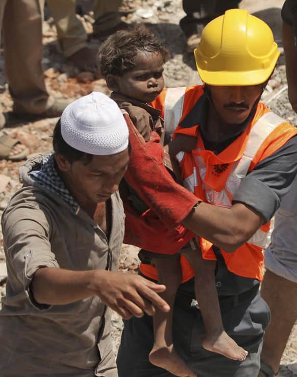 Rescue workers carry a young child who survived a building collapse on the outskirts of Mumbai.