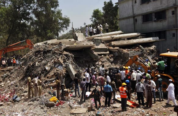 People gather around a heap of debris at the site of a building collapsed as a rescue operation continues on the outskirts of Mumbai.