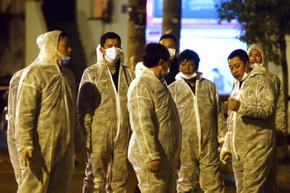 Workers in protective clothing chat during a culling operation as authorities detected the new bird flu strain in pigeons being sold for meat at a wholesale market in Shanghai.