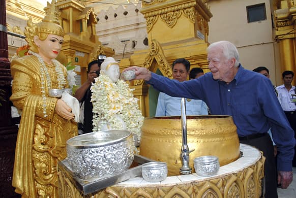 Former US President Jimmy Carter pours water on a Buddha statue as he visits the famed Shwedagon Pagoda, in Yangon, Myanmar. Carter arrived in Myanmar Tuesday to support the country`s ongoing democratic transition.