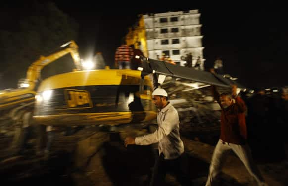 Rescue workers carry a stretcher near the site where a residential building collapsed in Thane, Mumbai.