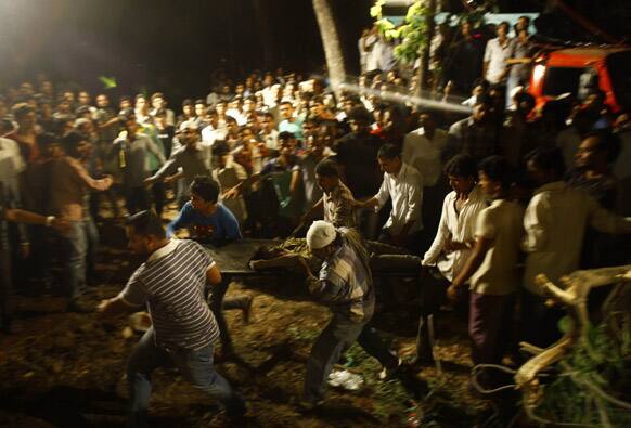 Rescue workers carry the body of a man near the site of a residential building which collapsed in Thane, Mumbai.