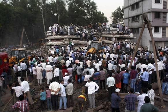 People gather as rescue workers look for trapped people after a building collapsed in Thane, Mumbai.