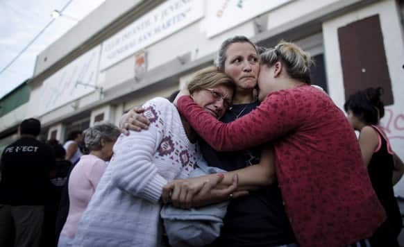 People embrace outside a club where the Red Cross set up a center to help flood victims in La Plata, in Argentina`s Buenos Aires province. Buenos Aires Gov. Daniel Scioli says 49 people died in this flooded capital of Argentina’s largest province as torrential rains swamped entire neighborhoods.