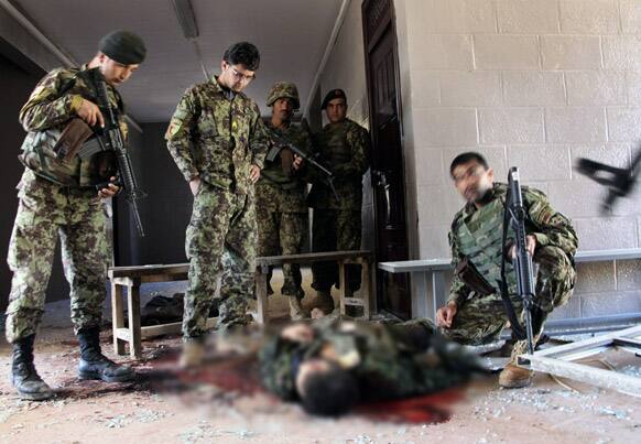 Afghan army soldiers stand around a killed Taliban, dressed as an Afghan army soldier, in the destroyed courthouse in Farah, western Afghanistan.
