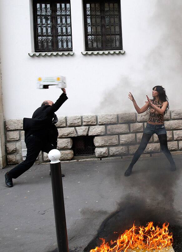 A man throws a box toward a FEMEN activist during a protest in front of the Grand Mosque in Paris.