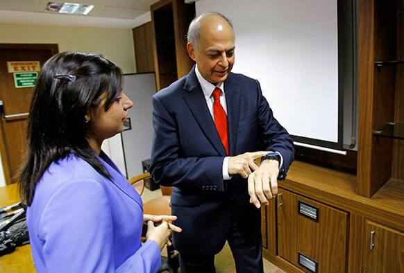 Ranjit Shahani, vice chairman and managing director of Novartis India Limited, right, checks time as he speaks to a reporter after a news conference in Mumbai.