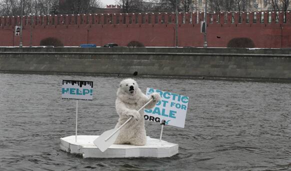 A greenpeace activist dressed as a polar bear sits on a wooden block of ice on the Moskva River protesting against plans of oil companies` drilling in the Arctic, with the Kremlin wall in the background, in Moscow, Russia.