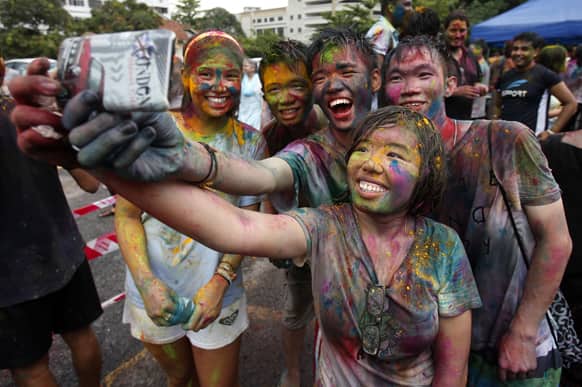 Teenagers, faces smeared with colored powder, take a photo with a mobile phone during a religious spring festival Holi in Kuala Lumpur, Malaysia.