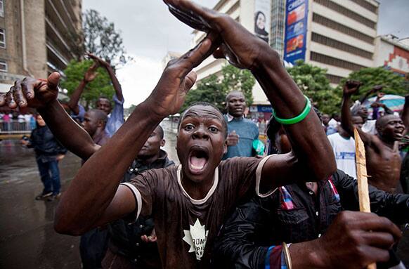 A supporter of losing presidential candidate Raila Odinga gestures as he protests with others in the rain in front of riot police guarding the Supreme Court in Nairobi, Kenya.