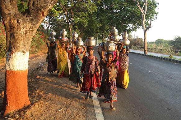 Indian women return to their homes after collecting drinking from a nearby water tank on the outskirts of Vadodara in Indian state of Gujarat.
