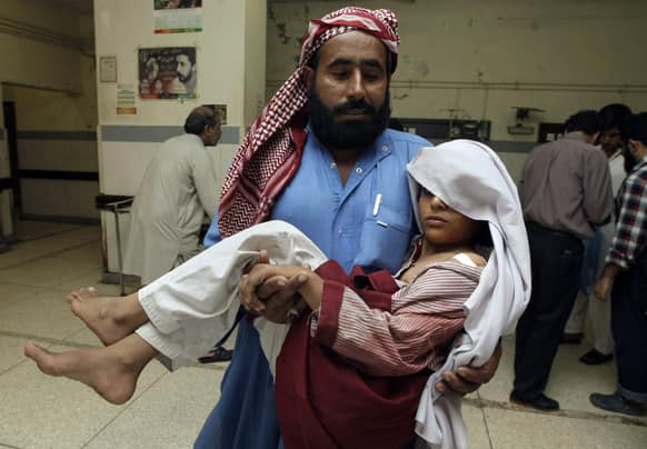 A Pakistani man carries his child who was injured in a grenade attack, inside a local hospital in Karachi, Pakistan.