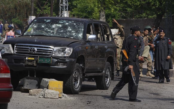 Pakistani troops gather next to a damaged vehicle which was used by a paramilitary police commander at the site of a suicide bombing in Peshawar.
