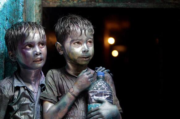 Bangladeshi Hindu children smeared in colors stand at a doorway as they watch Holi festival celebrations in Dhaka.