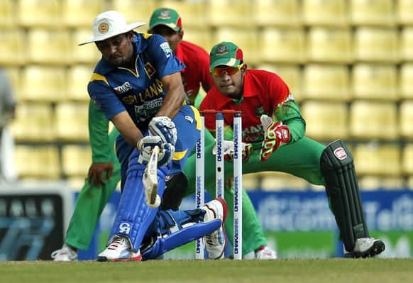 Tillakaratne Dilshan bats as Bangladesh`s wicketkeeper Mushfiqur Rahim watches during the third one day international cricket match between Sri Lanka and Bangladesh in Pallekele, Sri Lanka.