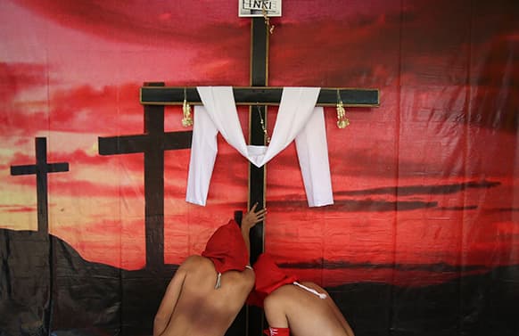 Filipino hooded penitents stop to pray at one of the stations of the cross during Maundy Thursday rituals to atone for sins, in suburban Mandaluyong, east of Manila, Philippines.
