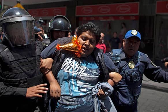 An alleged worker of La Merced market is detained by police officers during a protest in downtown Mexico City.