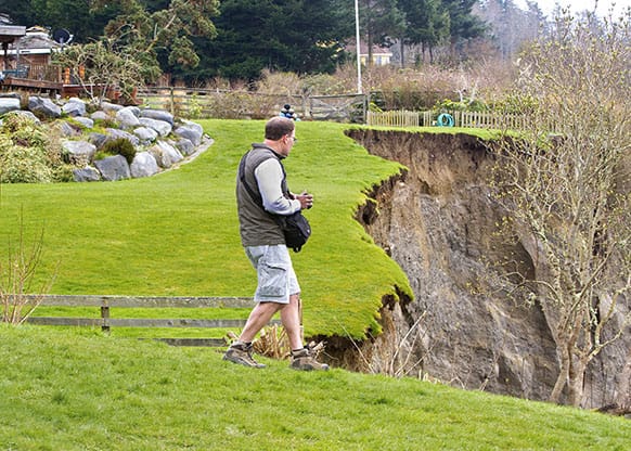 Geologist Terry Swanson from the University of Washington surveys the damage from a landslide on Whidbey Island near Coupeville, Wash.