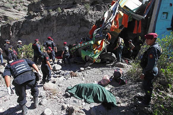 Police officers stand near the dead body of a passenger after a bus crashed in the southern department of Arequipa, Peru. At least 24 people were killed and 18 were injured when the passenger bus plunged 100 meters (328 feet) into a ravine in the Arequipa-Puno road.