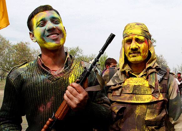 Indian Border Security Force soldiers with their faces smeared with colored powder pose for photographs as they celebrate Holi, inside their base camp on the outskirts of Srinagar.