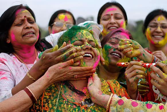 Women smear colors on each others faces as they celebrate