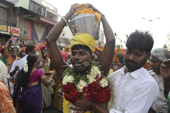 A Hindu devotee, his tongue pierced with a metal rod, participates in a religious procession during Panguni Uthiram festival in Ahmedabad.