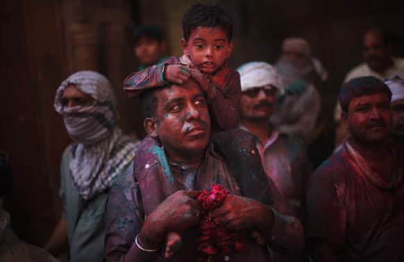 A child sits on the shoulders of a Hindu devotee inside Banke Bihari temple during Holi festival celebrations in Vrindavan.